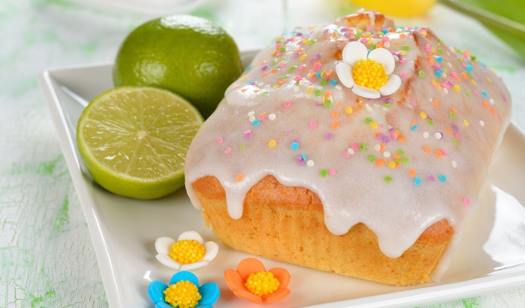 Красивый пасхальный кулич на белой тарелке с лаймом и сахарными цветами