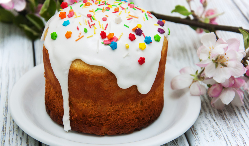 Красивый кулич с белой глазурью на столе с веткой яблони на Великий праздник Пасха