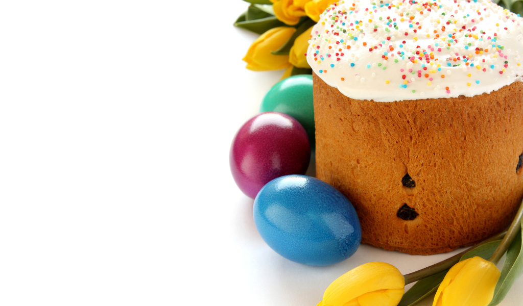 Красивый праздничный кулич с желтыми тюльпанами и крашеными яйцами на белом фоне к Пасхе