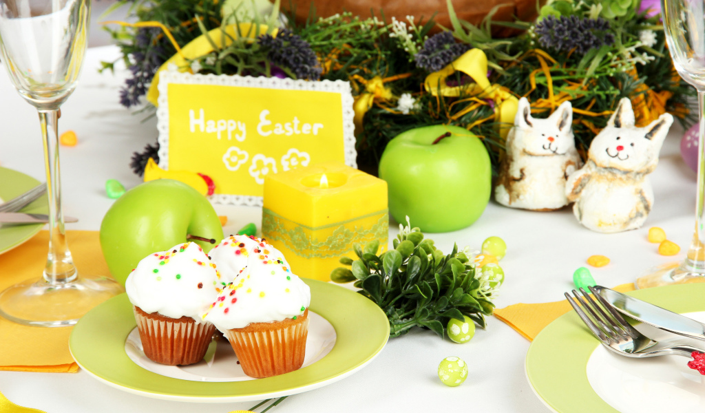 Накрытый пасхальный стол с кексами и зажженной свечой 