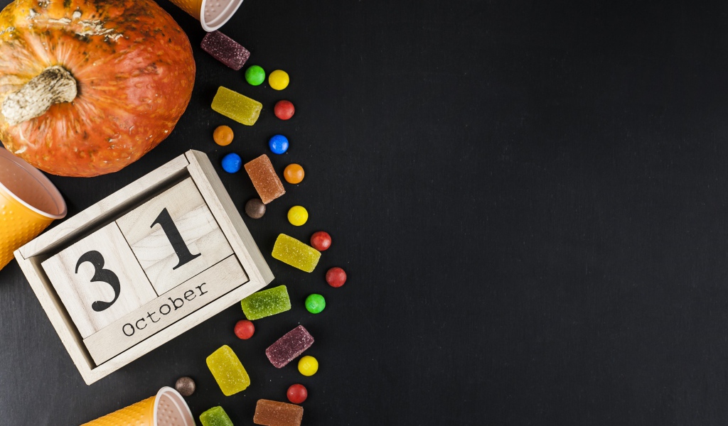 Конфеты, тыква и календарь на сером фоне на Хэллоуин