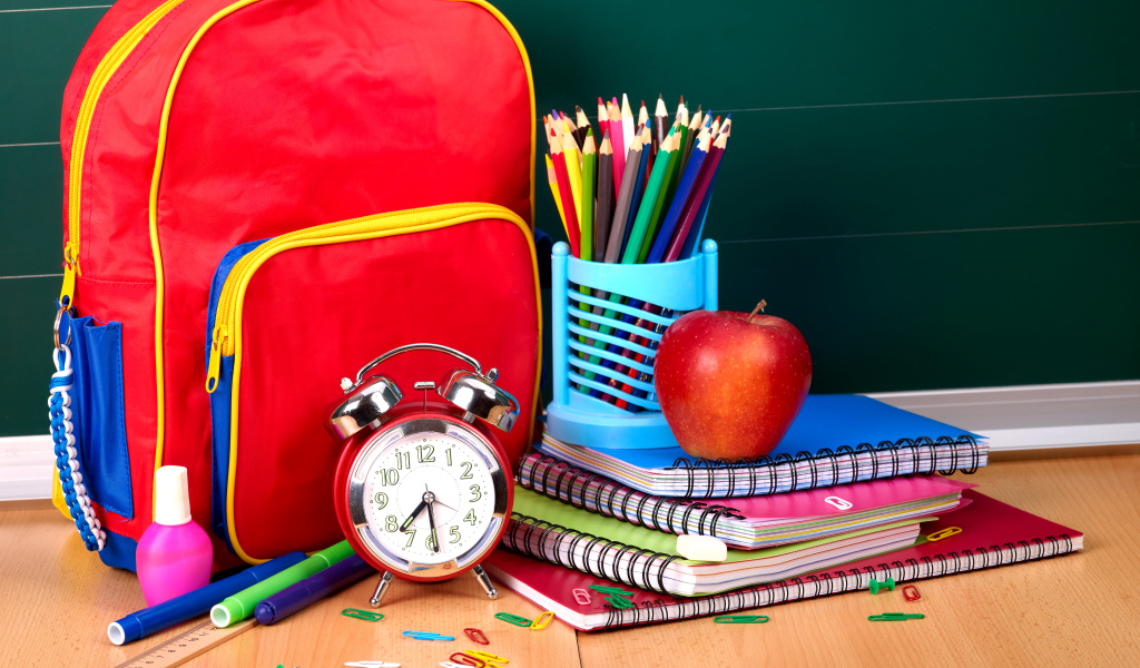 Рюкзак, тетради, карандаши, будильник и яблоко на День знаний 1 сентября