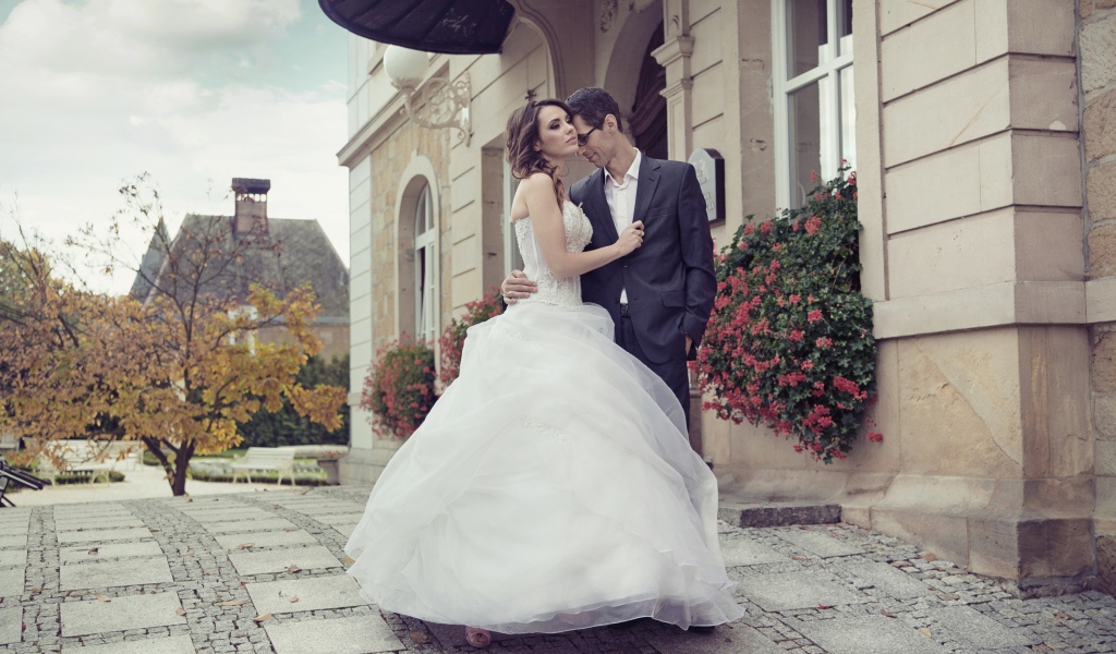 Жених и невеста стоят у здания 