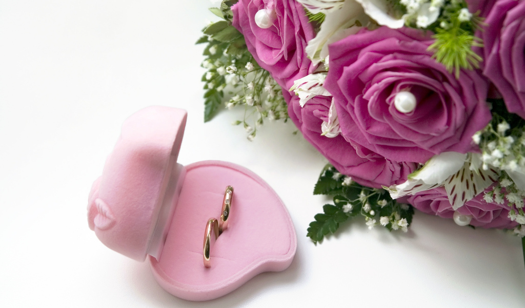 Два обручальных кольца в коробочке на белом фоне с букетом роз