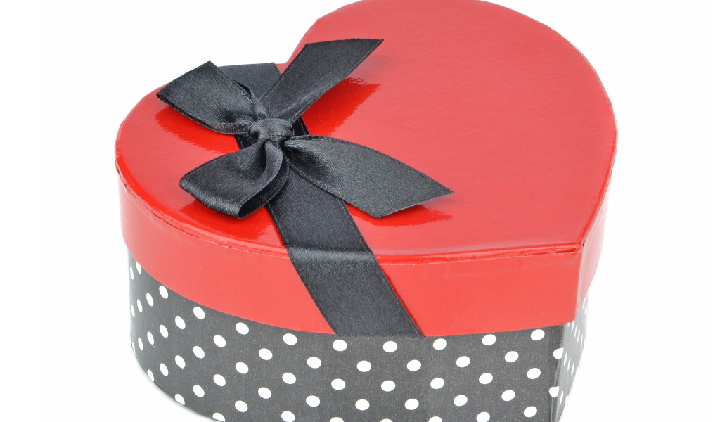 Красивая коробка в форме сердца с черным бантом на белом фоне