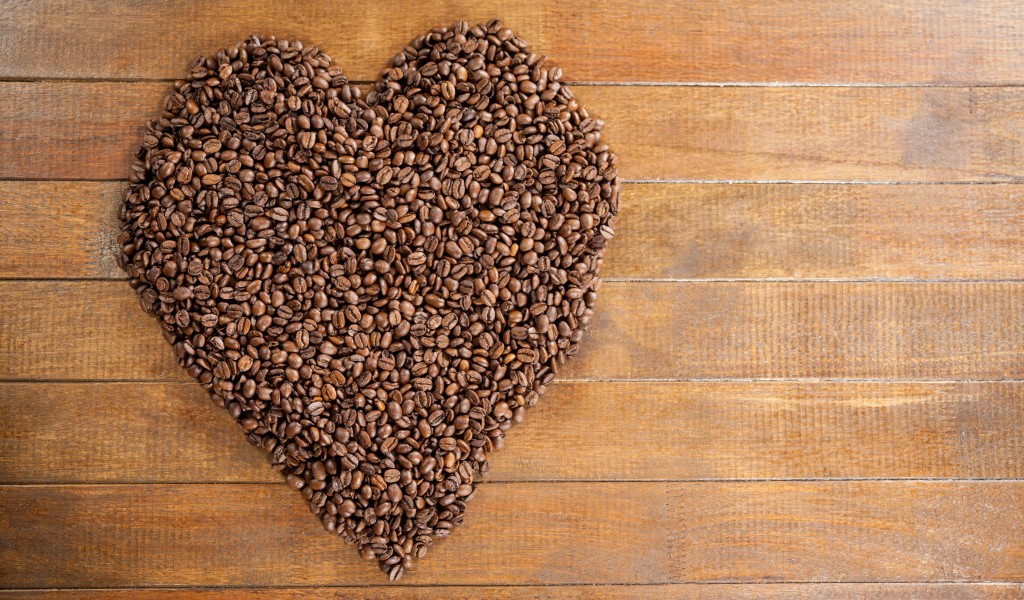 Большое сердце из кофейных зерен на деревянном столе