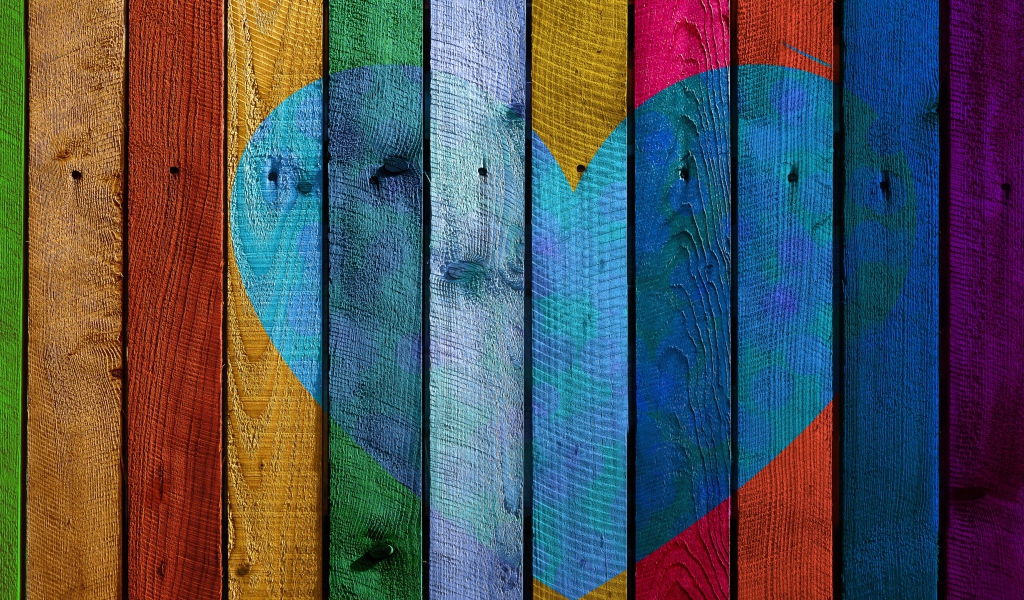 Голубое сердце нарисовано на разноцветном заборе