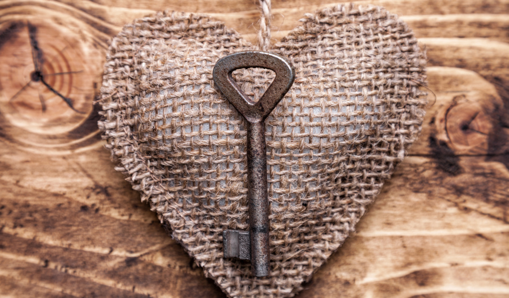 Сердечко из мешковины с ключом на деревянном фоне