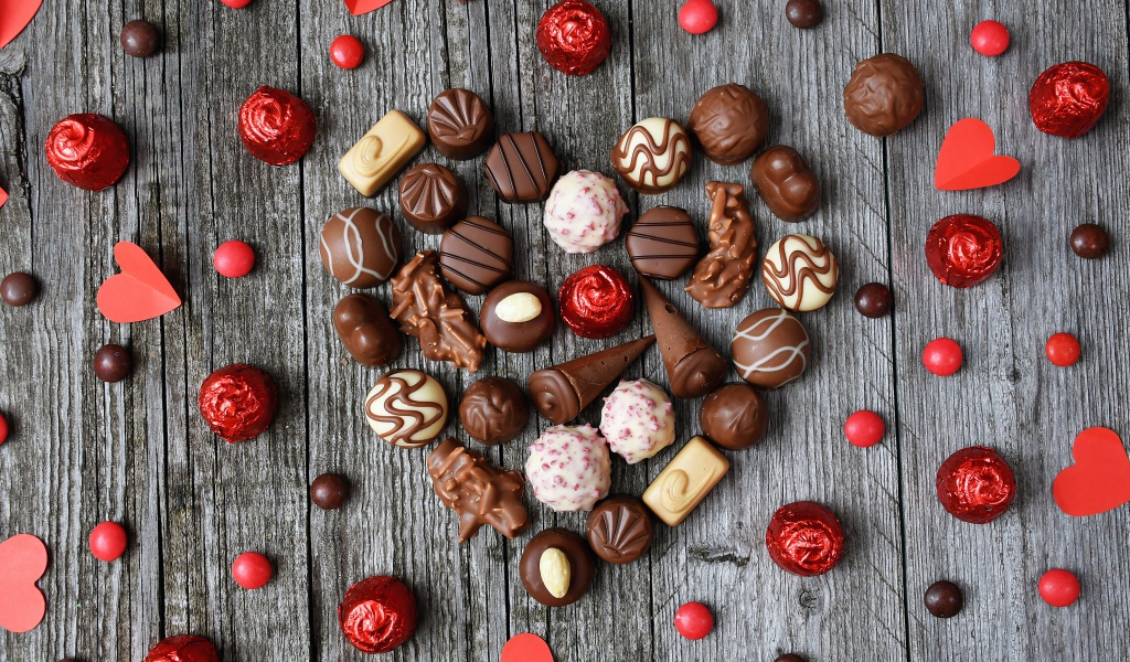 Сердце из шоколадных конфет ассорти на деревянном столе для любимой 