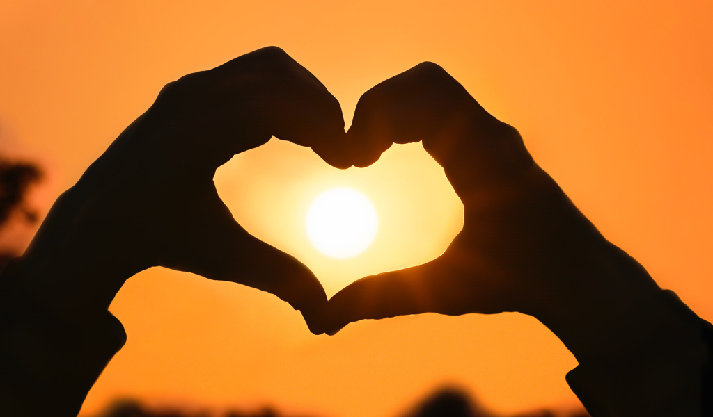 Сердце руками на фоне солнца в небе