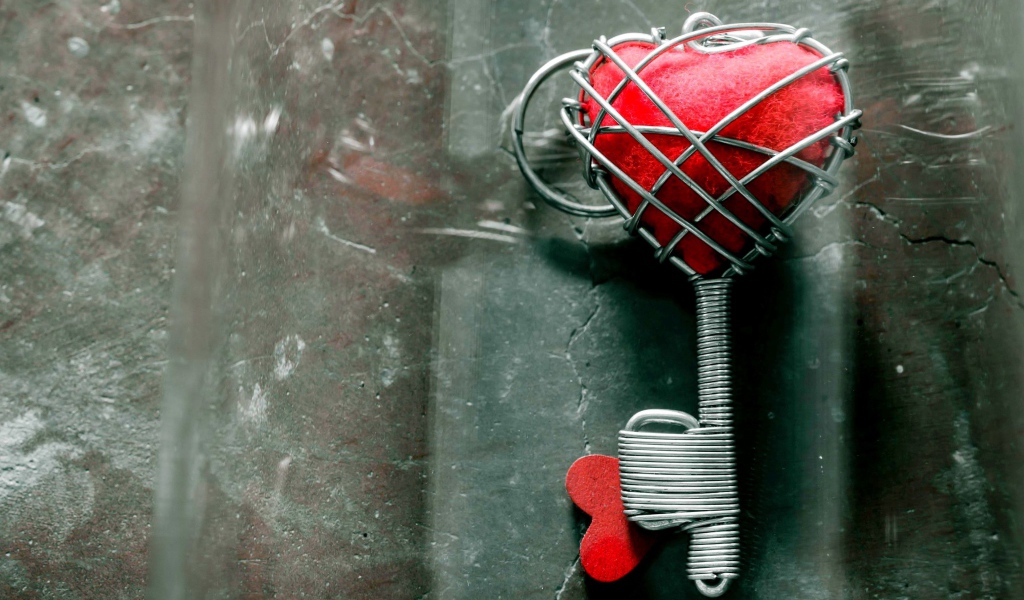 Ключ с красным сердцем на сером столе