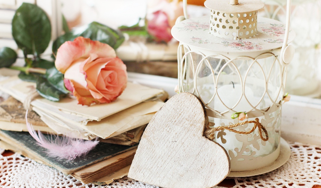 Фонарь со свечей на столе с розой, сердцем и книгами