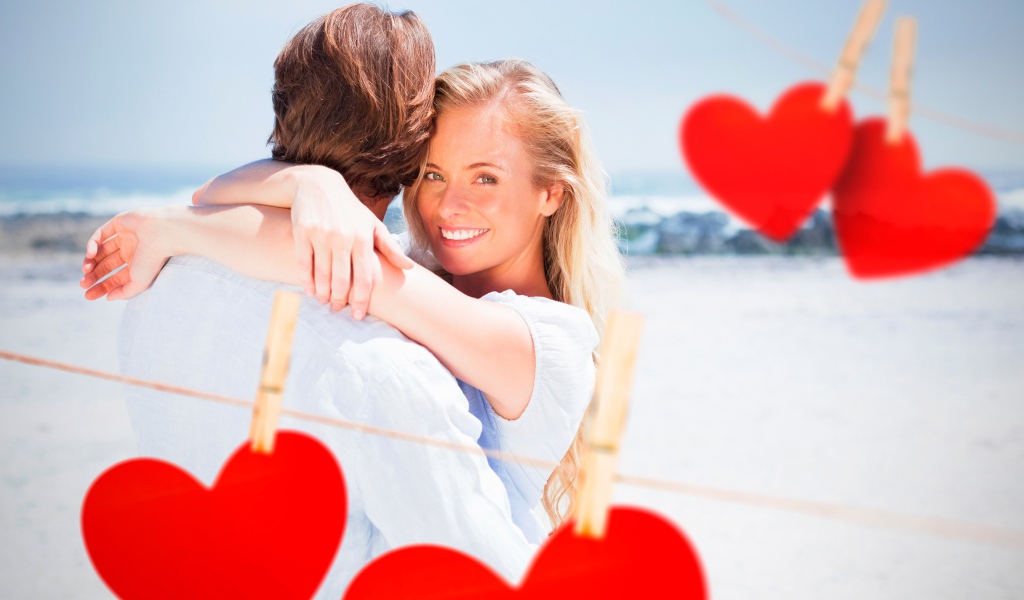 Влюбленная пара с красными сердечками на берегу океана