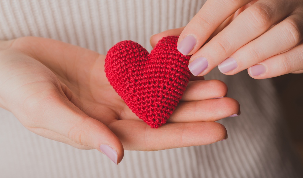 Красное вязаное сердце в руках у девушки