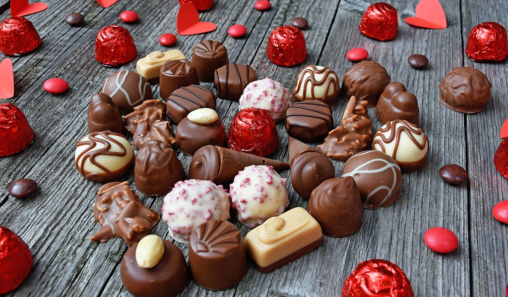 Сладкое сердце из шоколадных конфет на деревянном столе