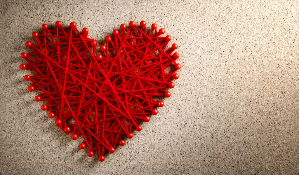 Сердце из красных нитей и невидимок на сером фоне