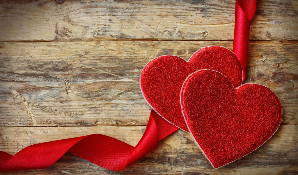 Два сердца с красной лентой на деревянном столе