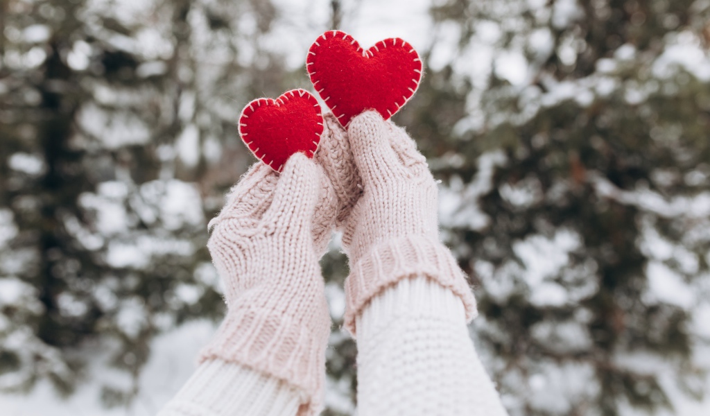 Два красных сердечка из ткани в руках у девушки 