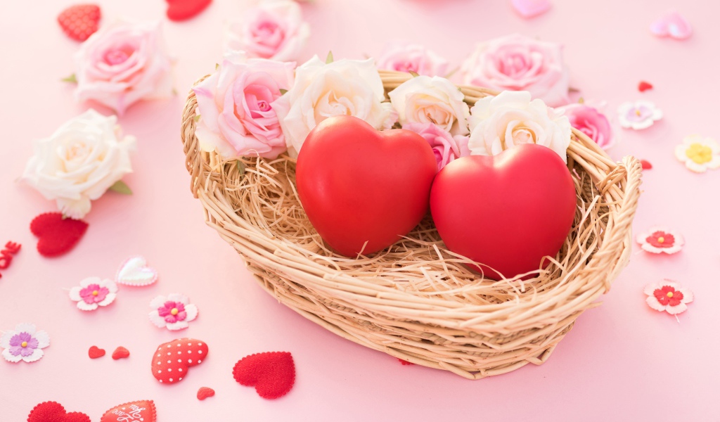 Two red hearts lie in a basket with roses