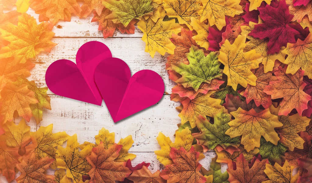 Два красных сердца на столе с желтыми листьями
