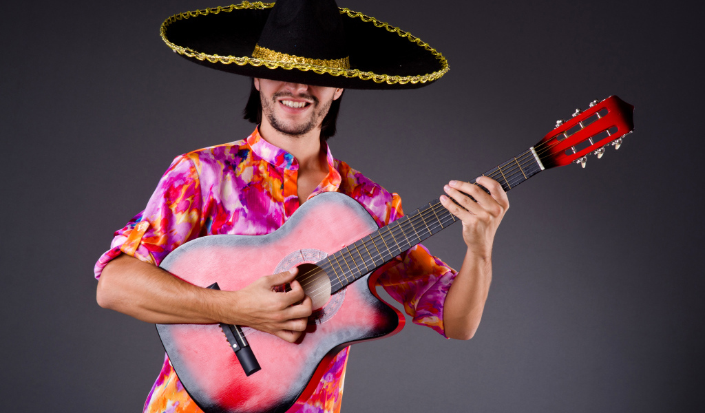 A man in a sombrero with a guitar in his hands on a gray background
