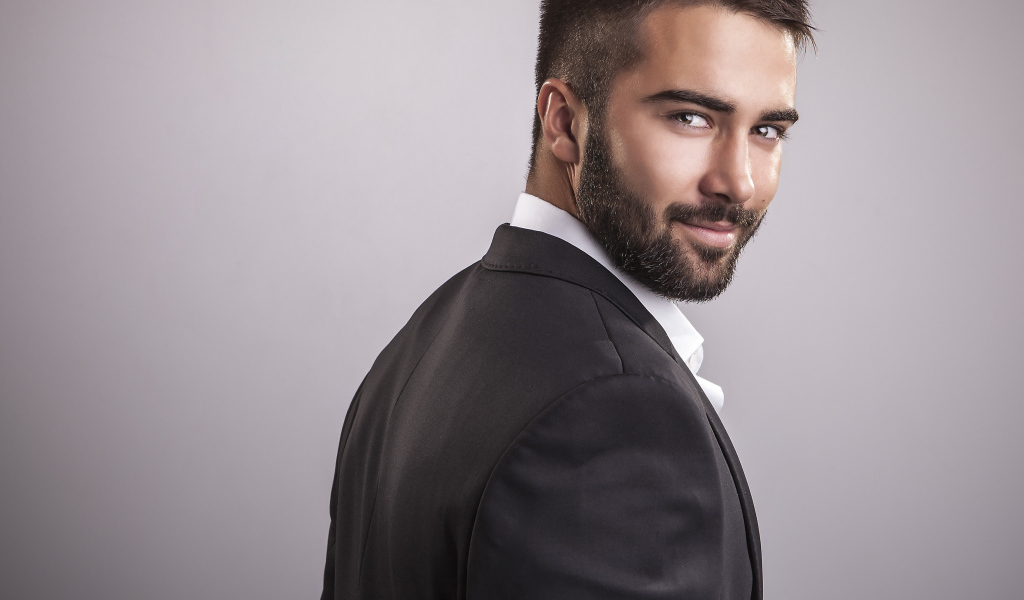 Красивый мужчина модель с бородой на сером фоне