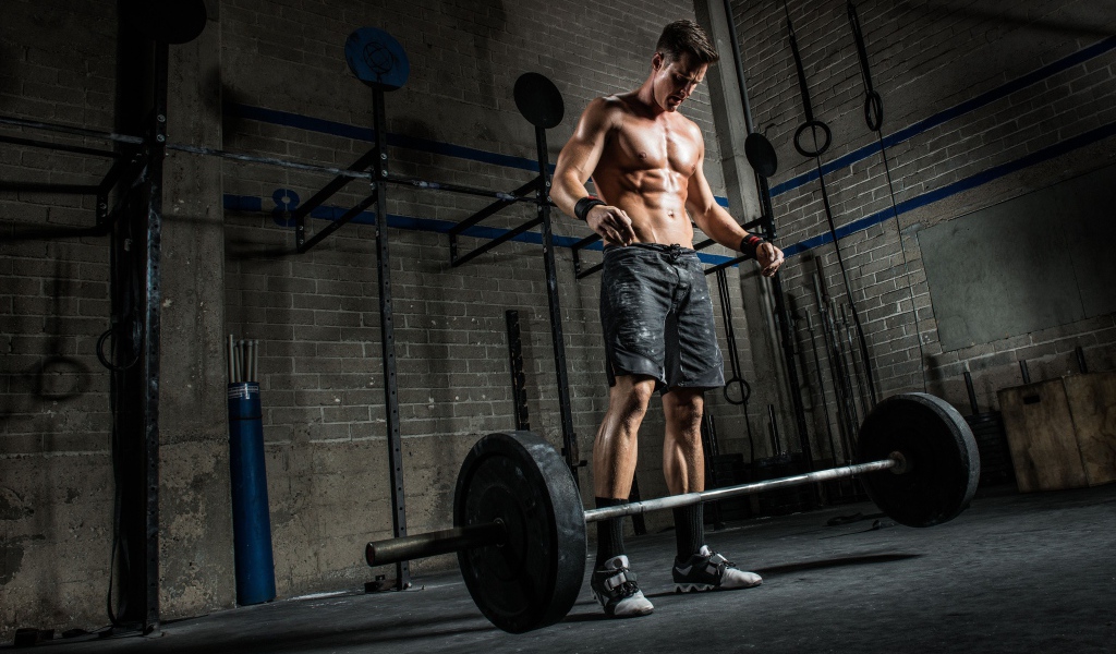 Мужчина спортсмен поднимает штангу в спортзале