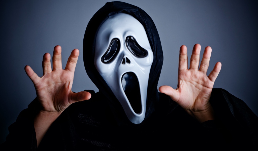 Мужчина в маске пугает на сером фоне