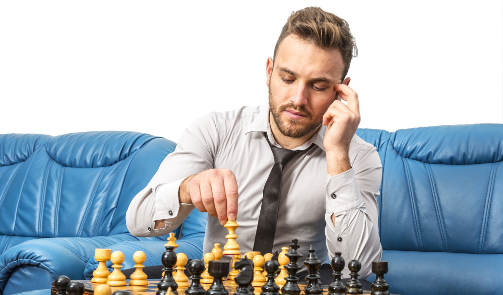 Мужчина играет в шахматы на синем диване