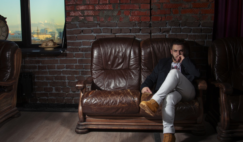 Стильный мужчина сидит в кожаном кресле 