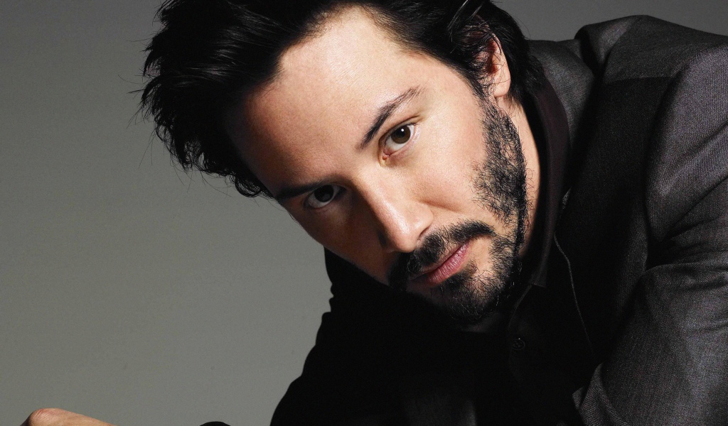 Актер Киану Ривз в костюме на сером фоне