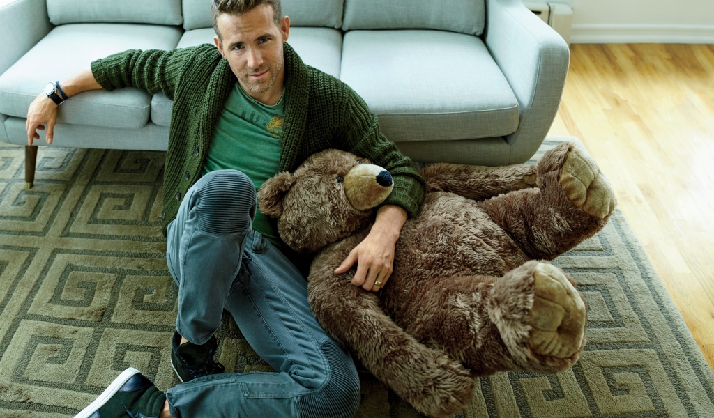 Актер Райан Рейнольдс с большим плюшевым медведем сидит на полу
