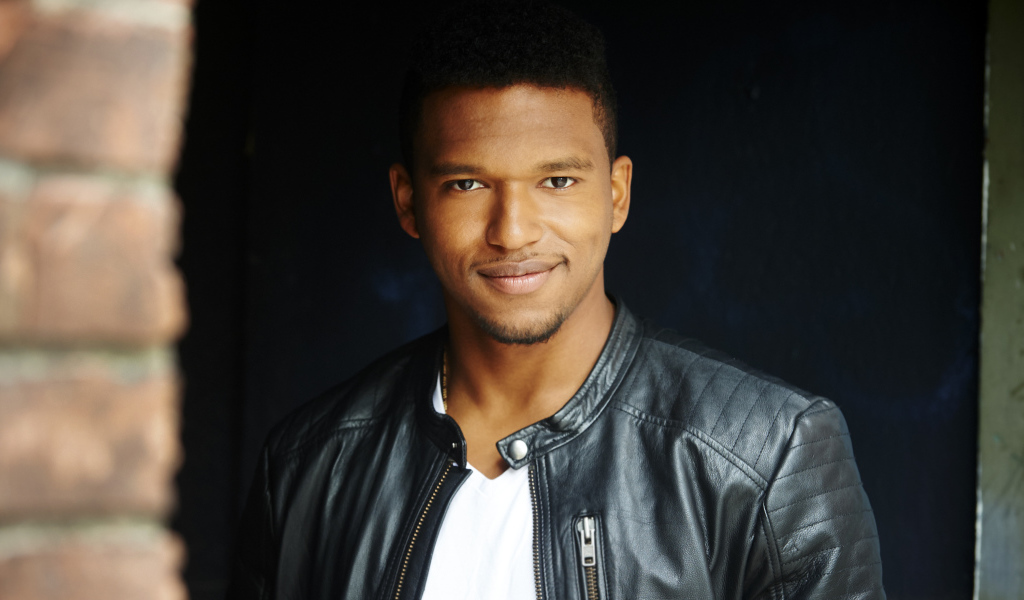 Красивый мужчина в черной куртке, актер Ловелл Адамс-Грей