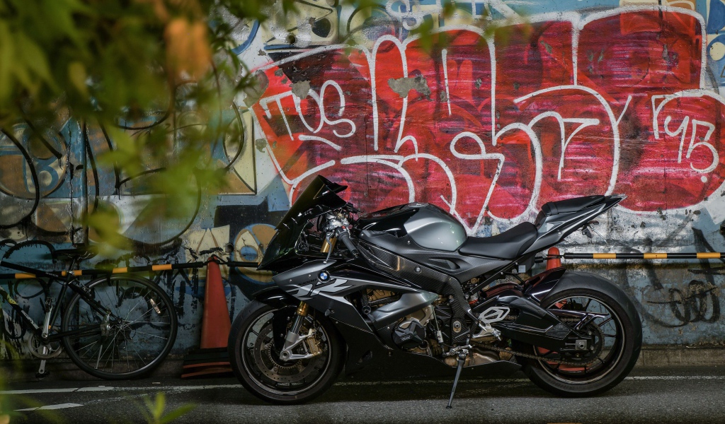 Черный мотоцикл BMW S1000RR на фоне разрисованной стены