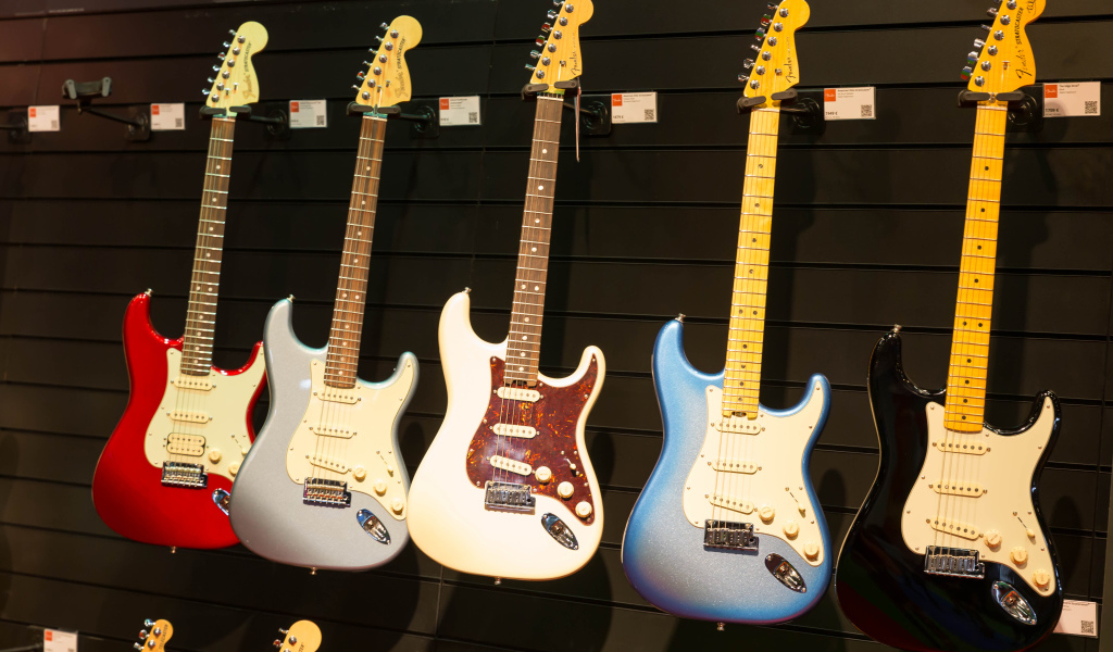 Много разноцветных электрогитар на стене 