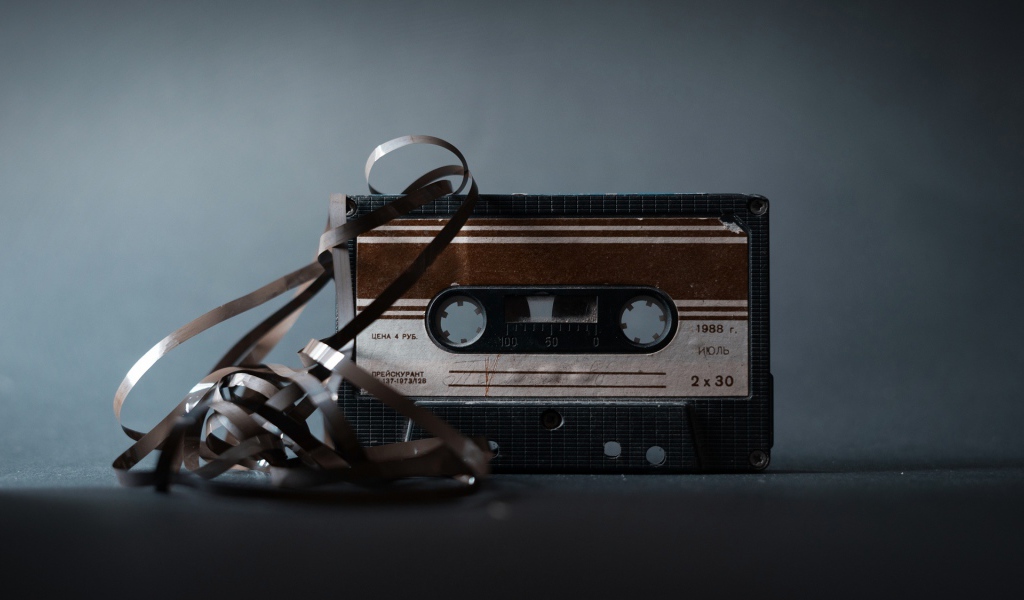 Старая кассета с вытянутой пленкой на сером фоне 