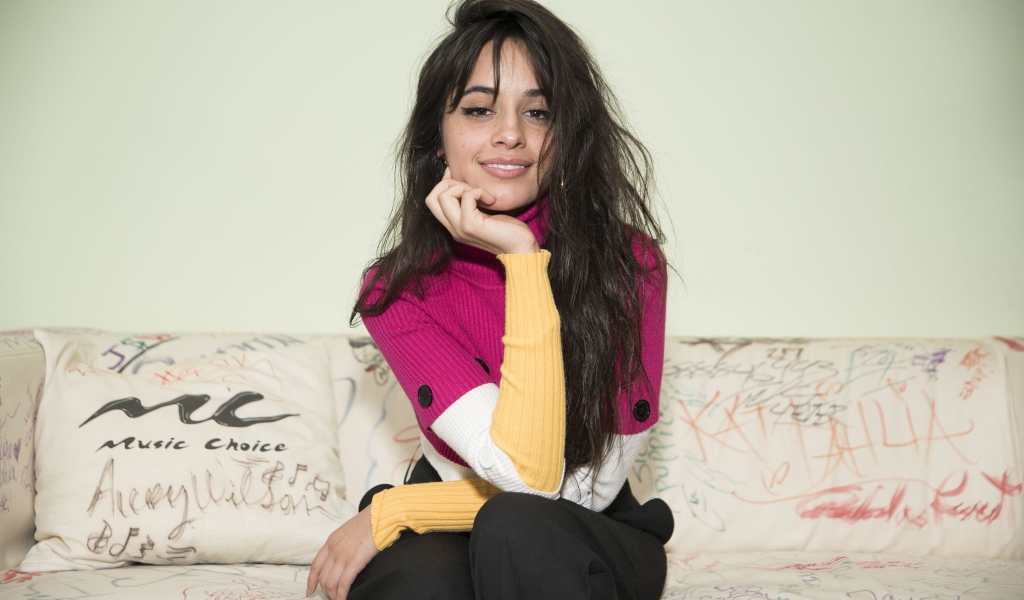 Улыбающаяся Камила Кабельо сидит на диване