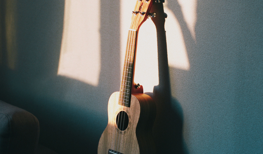 Желтая гитара стоит у серой стены