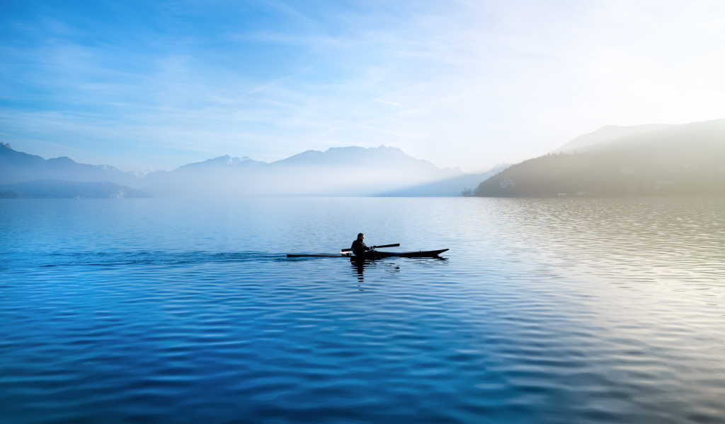A man floats on a boat on the background of mountains
