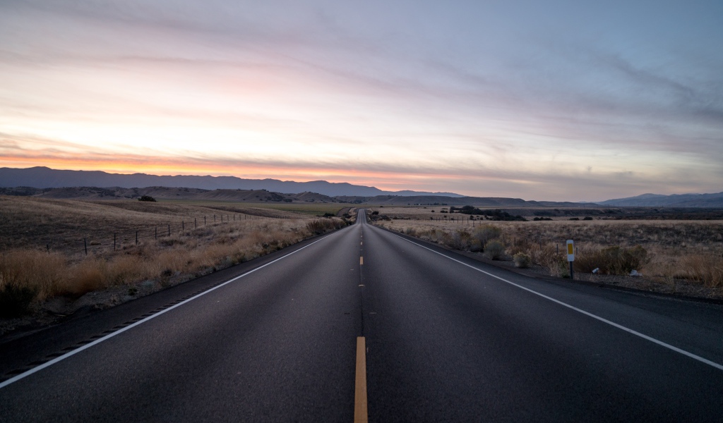 Асфальтная дорога уходит вдаль на фоне неба