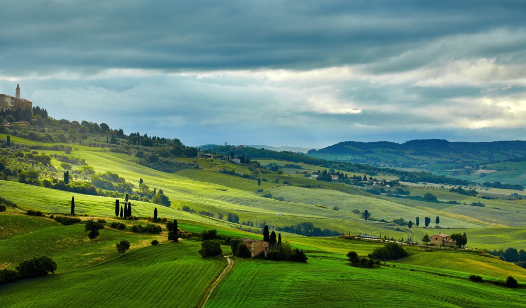 Зеленые поля под небом с грозовыми облаками