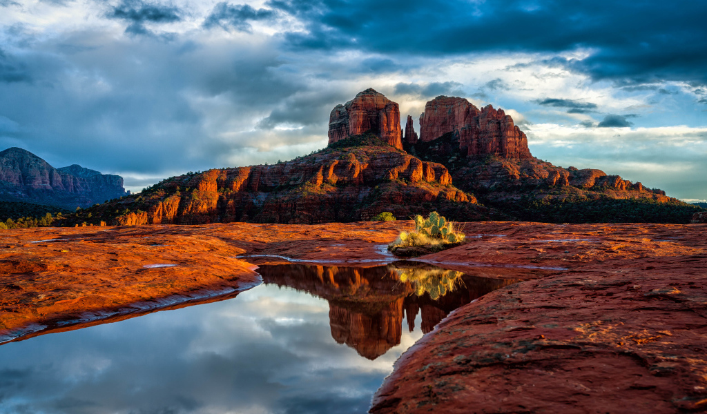 Скалы под пасмурным небом отражаются в воде