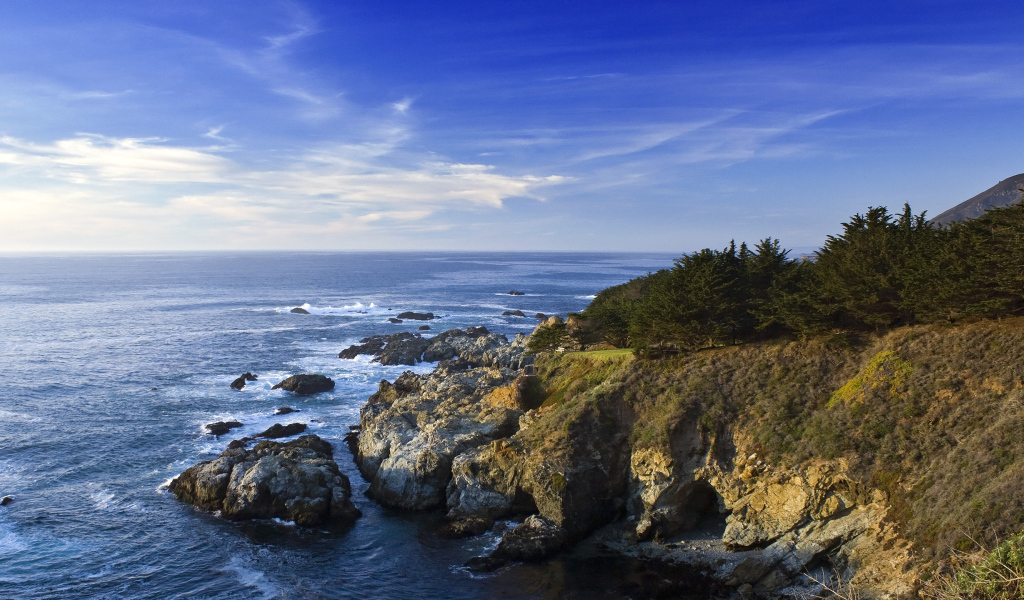 Каменные скалы береговой линии в океане под голубым небом