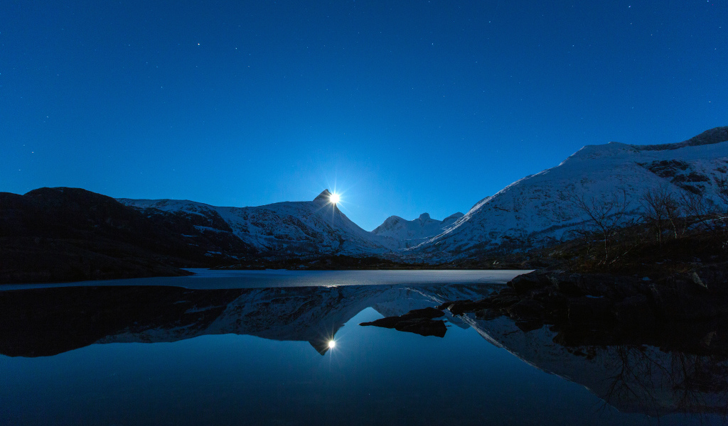 Луна и заснеженные горы отражаются в воде 