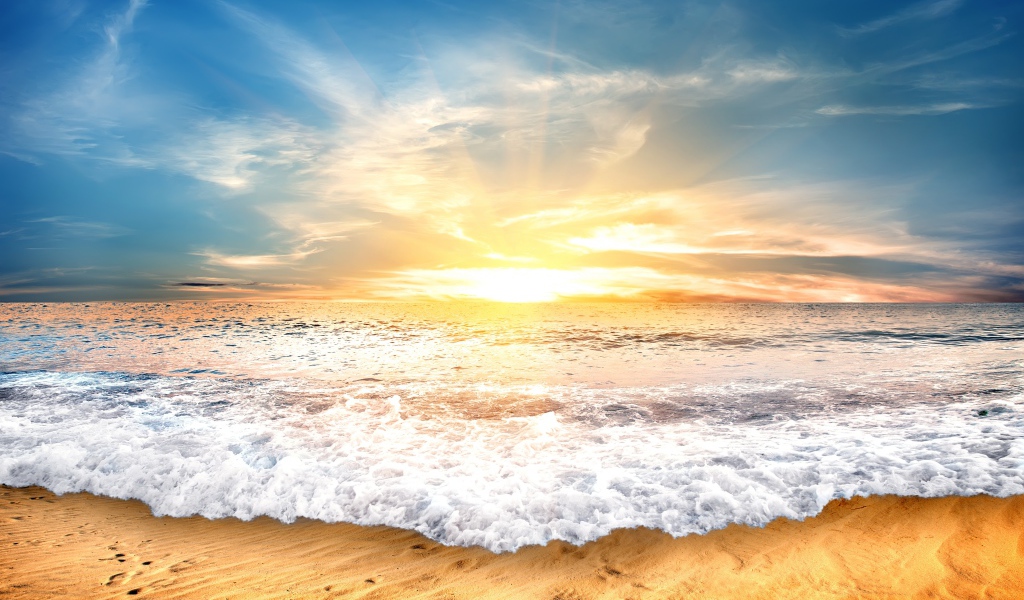 Белые волны на желтом песке на закате солнца 