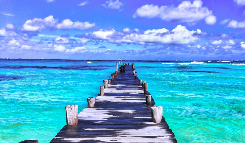 Деревянный мокрый пирс в голубом океане под красивым небом