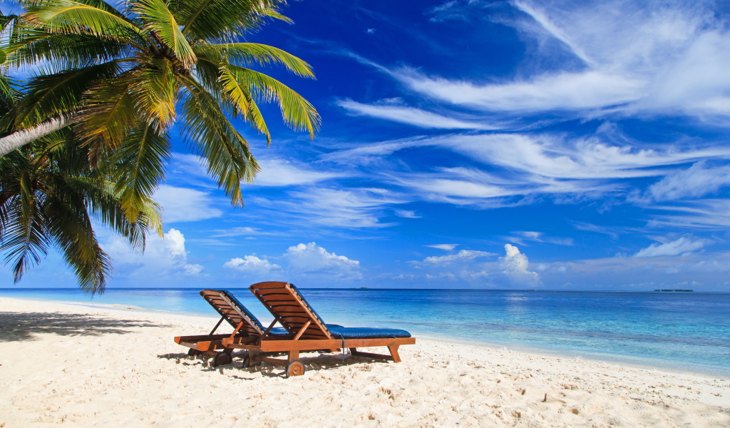Шезлонги на тропическом пляже под голубым небом