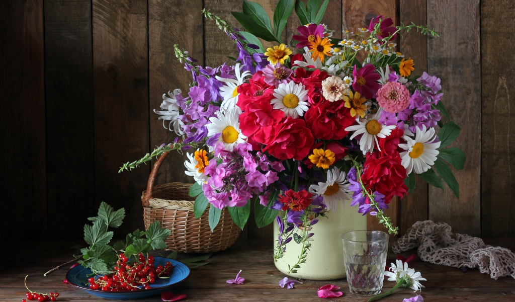 Красивый букет стоит на  столе с красной смородиной