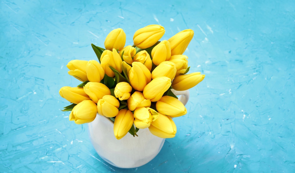 Букет оранжевых тюльпанов в белой вазе на голубом фоне