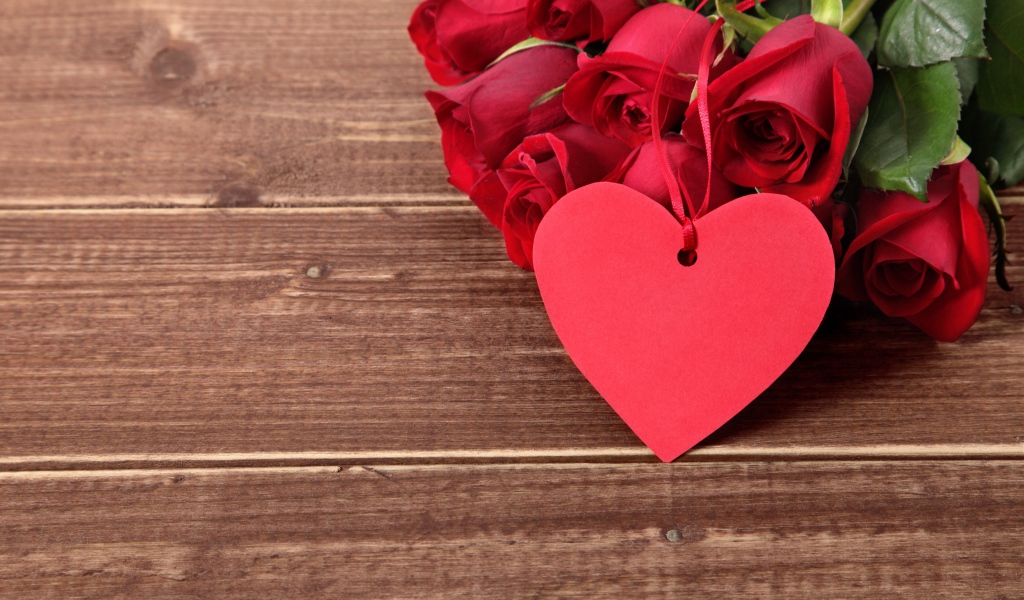 Букет красных роз на деревянном столе с красным сердцем